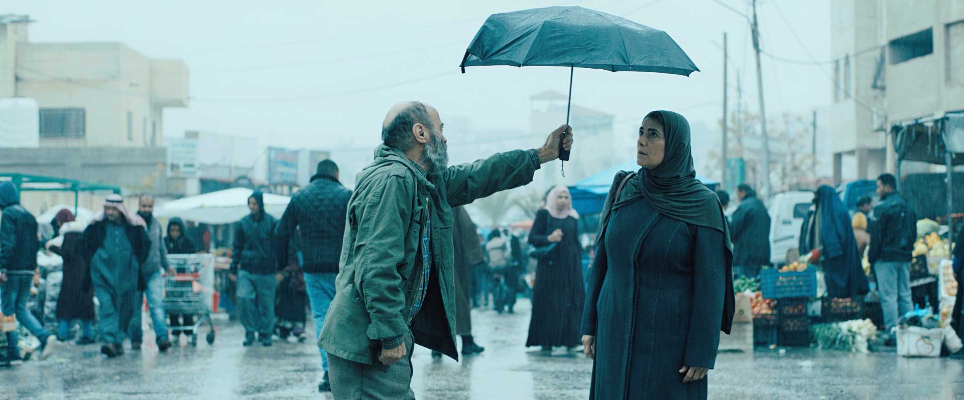 A man holding an umbrella for a woman in the street